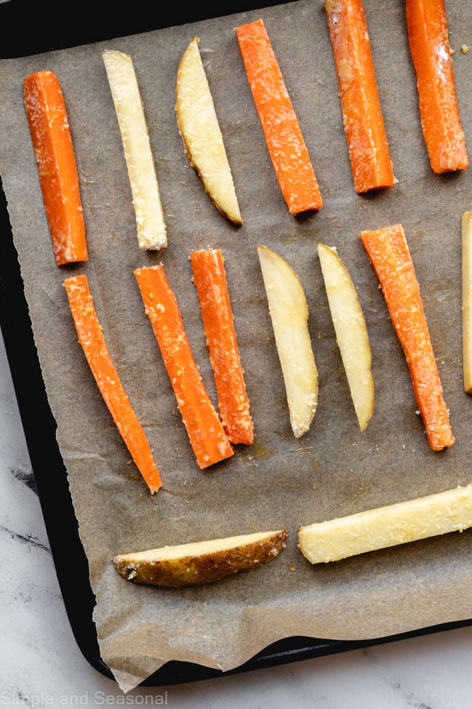 raw carrots and potatoes on parchment lined baking sheet