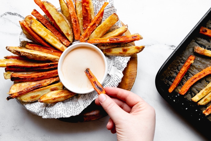 carrot fries and potato fries in a serving bowl, with the baking pan in the background