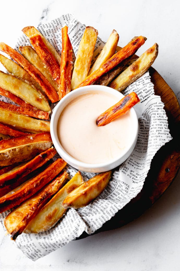 serving tray full of baked carrot fries, potato fries and dipping sauce