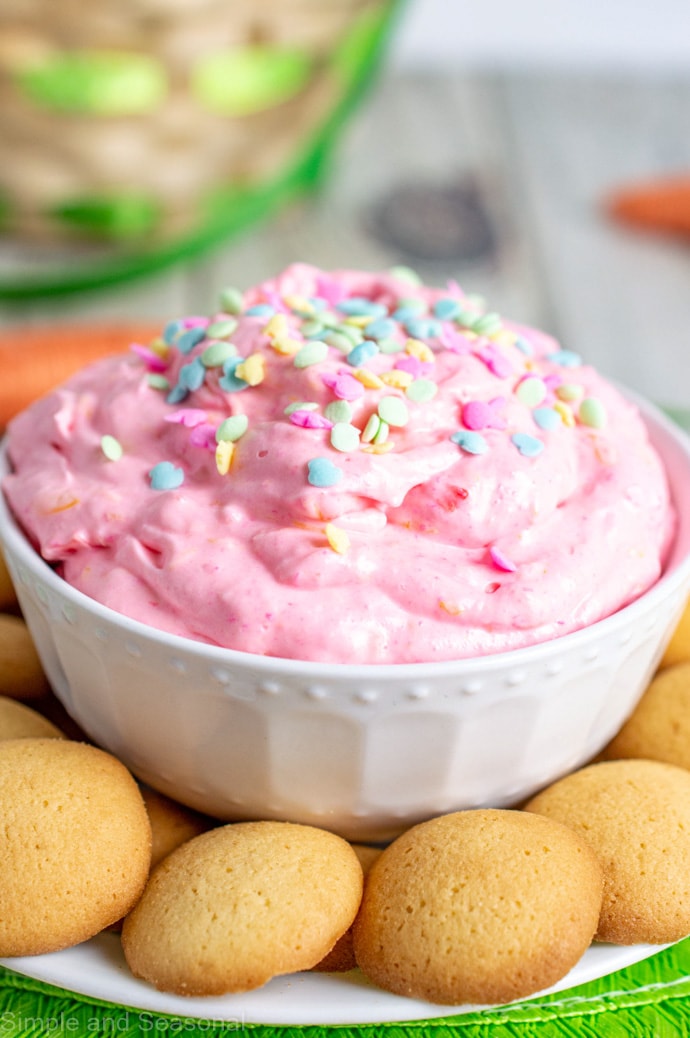 pink fruity cheesecake dip in a white bowl with an Easter basket in the background