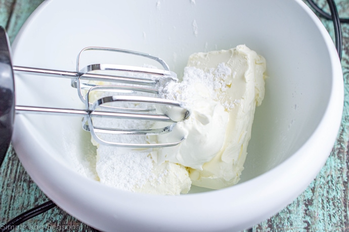 cream cheese, powdered sugar and sour cream in a bowl