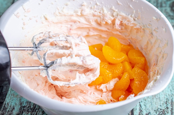 mandarin oranges in a bowl with the cheesecake mixture