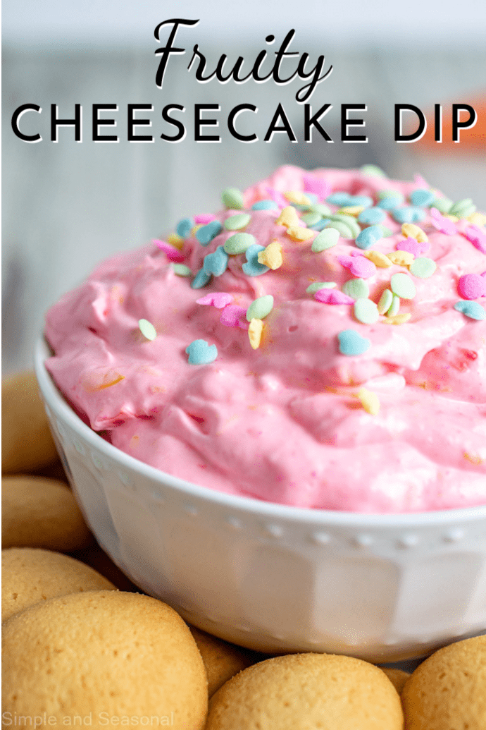 pink dip in a white bowl, with wafer cookies; text label reads Fruity Cheesecake Dip
