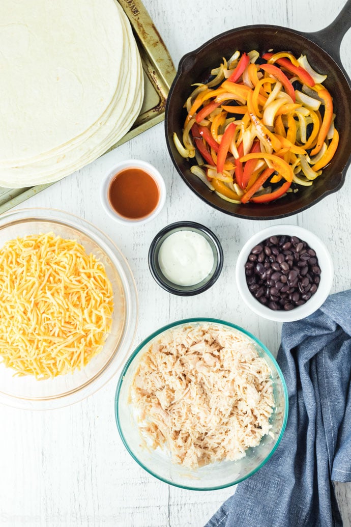 cheese, tortillas, chicken, sauce and peppers- ingredients for sheet pan buffalo chicken quesadillas