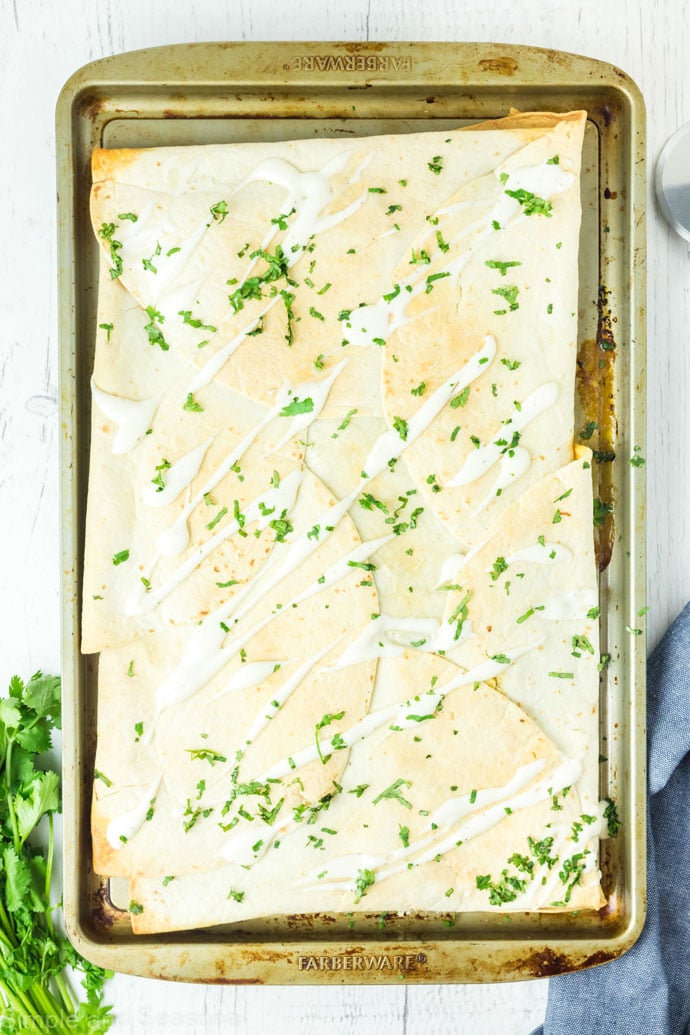 baked sheet pan chicken quesadillas topped with sour cream and cilantro