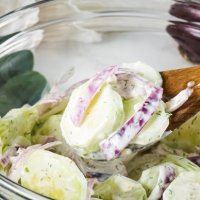 bowl of creamy cucumber salad with wooden spoon