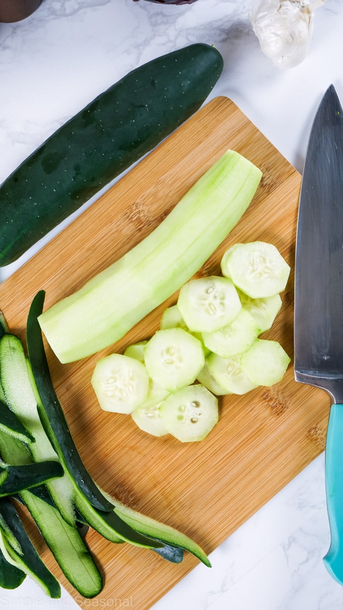 cucumber peeled and sliced on a cutting board