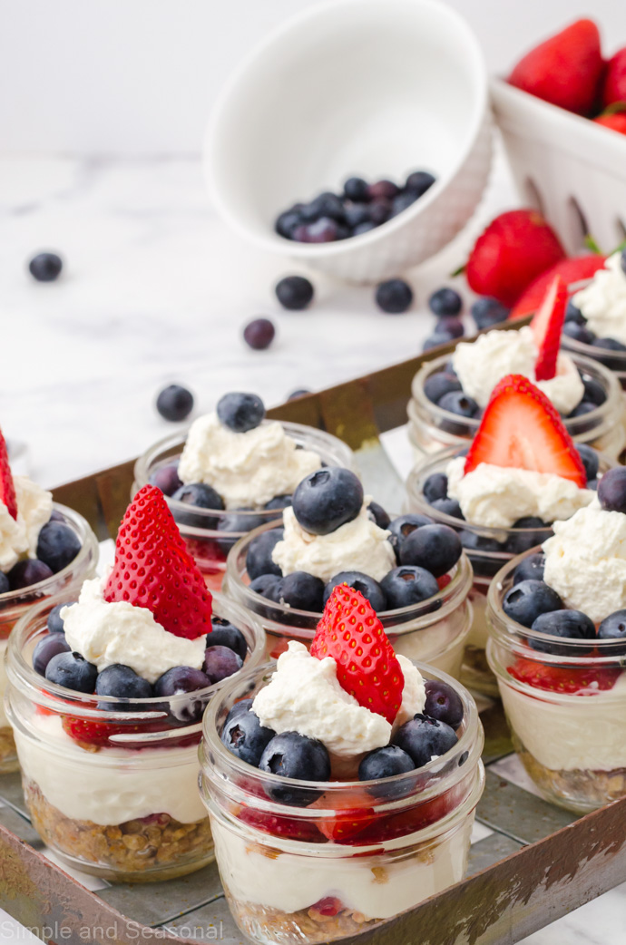 mini cheesecakes on a tray with blueberries and strawberries in the background