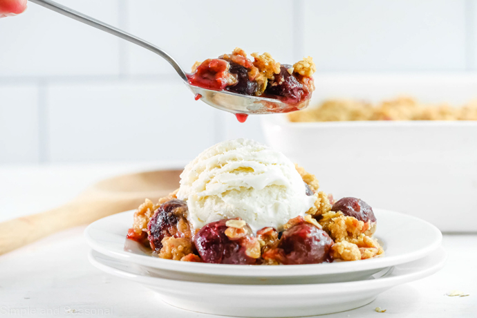 forkful of cherries and topping with plate in the background