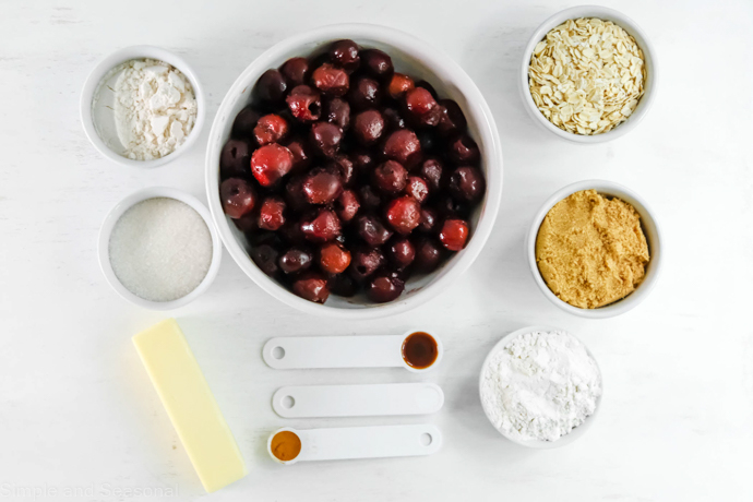 cherries in a bowl with other baking ingredients measured out in small bowls