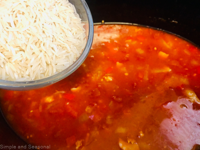 rice being added to cooking juices in the slow cooker