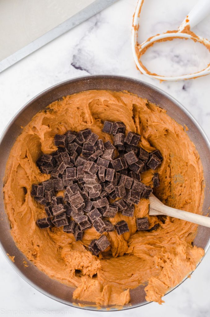 mixing bowl with blended pumpkin mixture and chocolate chunks on top