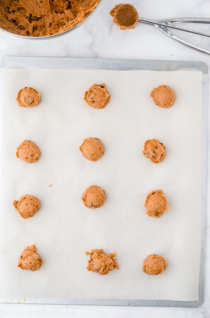 cookie dough balls on a parchment lined cookie sheet