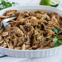 shredded pork in a white serving dish with blue striped towel underneath