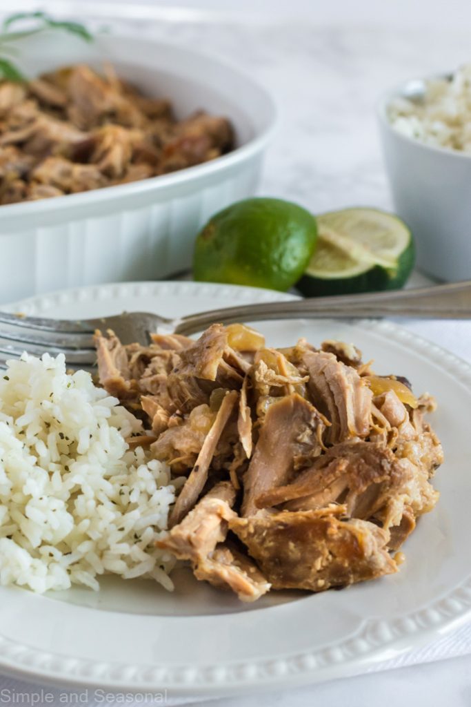 cuban pulled pork and rice on a white plate with serving dishes in the background
