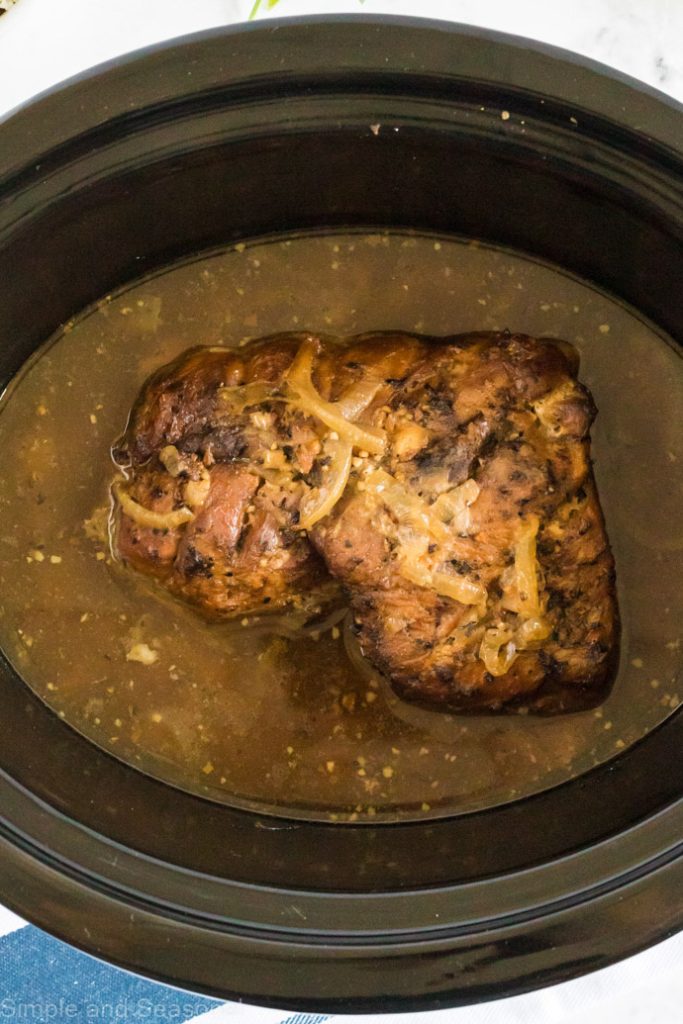 cooked Cuban pork in the slow cooker surrounded by cooking juices