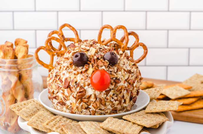 cheese ball rolled in pecans with added pretzel antlers and tomato nose