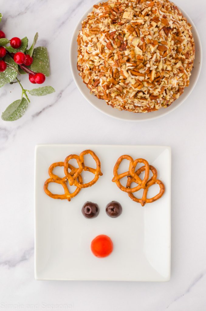 chopped pecans in a bowl and pretzels, olives and tomato on a plate