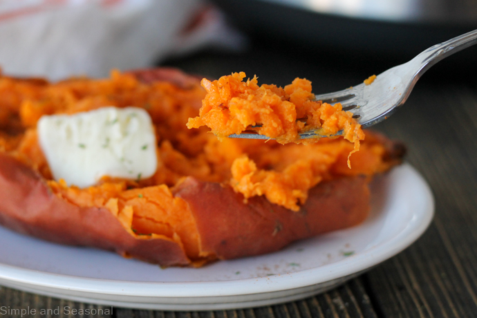 sweet potato on a fork with a cooked potato in the background