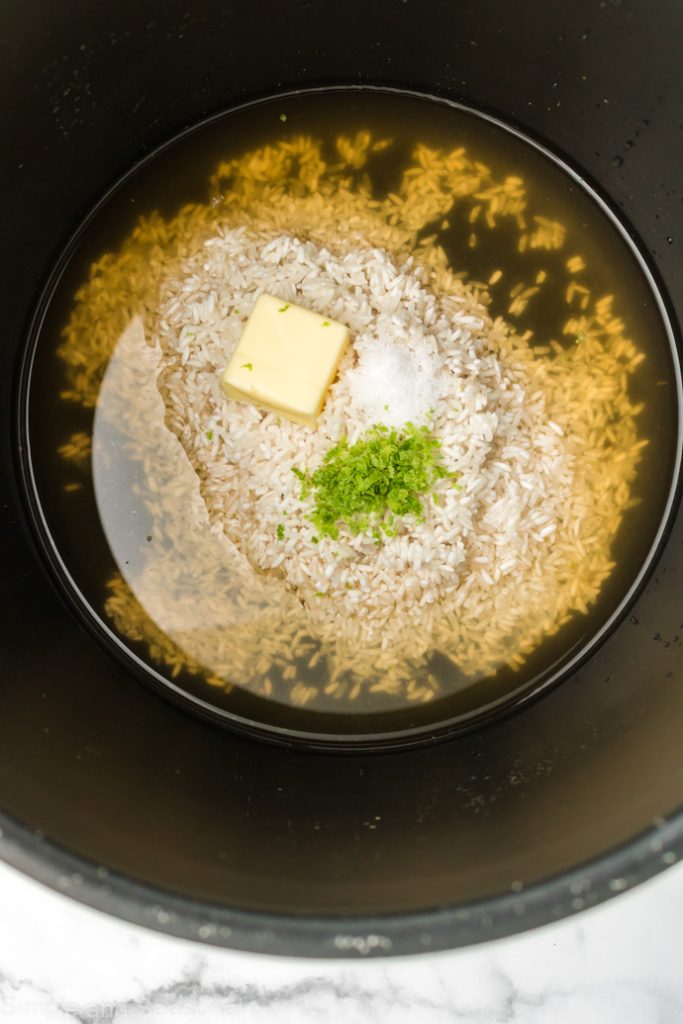 water, broth, rice, butter, salt and lime zest in the pot ready to cook