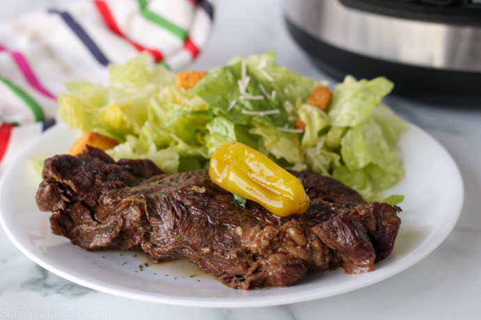 cooked roast on a plate with salad and pressure cooker in the background