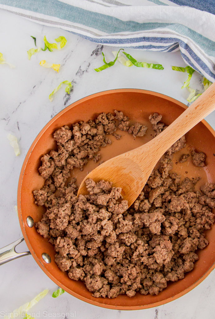 cooked ground beef in a pan with a wooden spoon