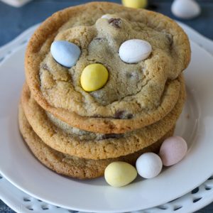 stack of three mini egg cookies on a white plate and blue background