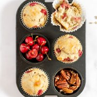 top down view of muffin pan with baked muffins and extra cherries and pecans