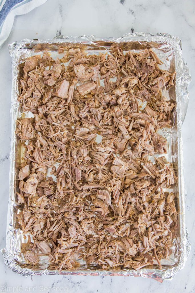 cooked pork laid out on a foil lined baking sheet