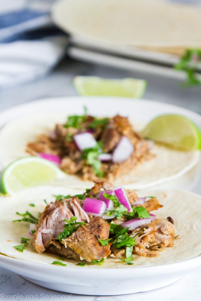 plate of pressure cooker carnitas with lime wedges