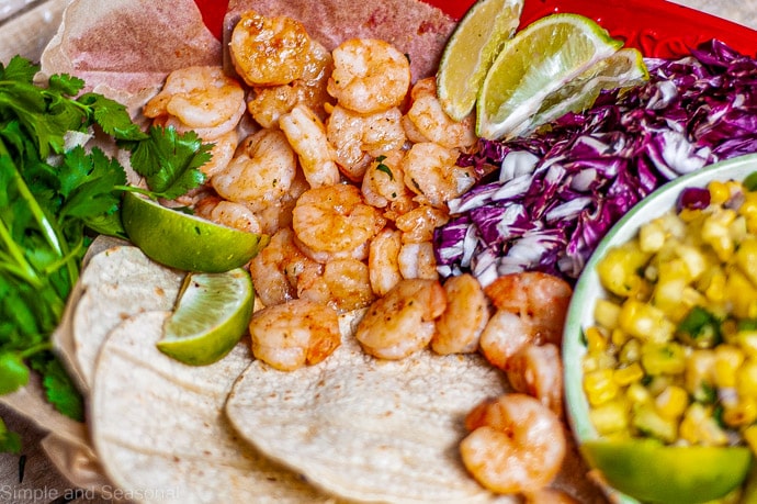 platter with cilantro, limes, shrimp, tortillas and corn salsa