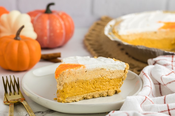 slice of no bake pumpkin pie showing three layers with whole pie in the background