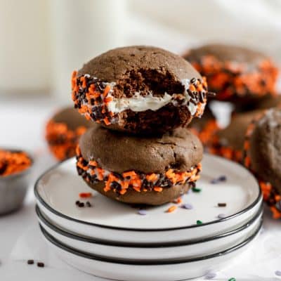 closeup of two whoopie pies on a plate with orange and black sprinkles.