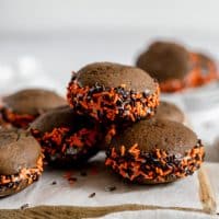close up view of chocolate sandwich cookies filled with cream and decorated with orange and black sprinkles
