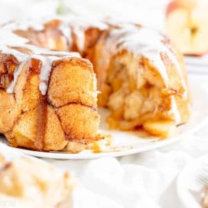 monkey bread with glaze on a platter, with pieces removed onto a plate