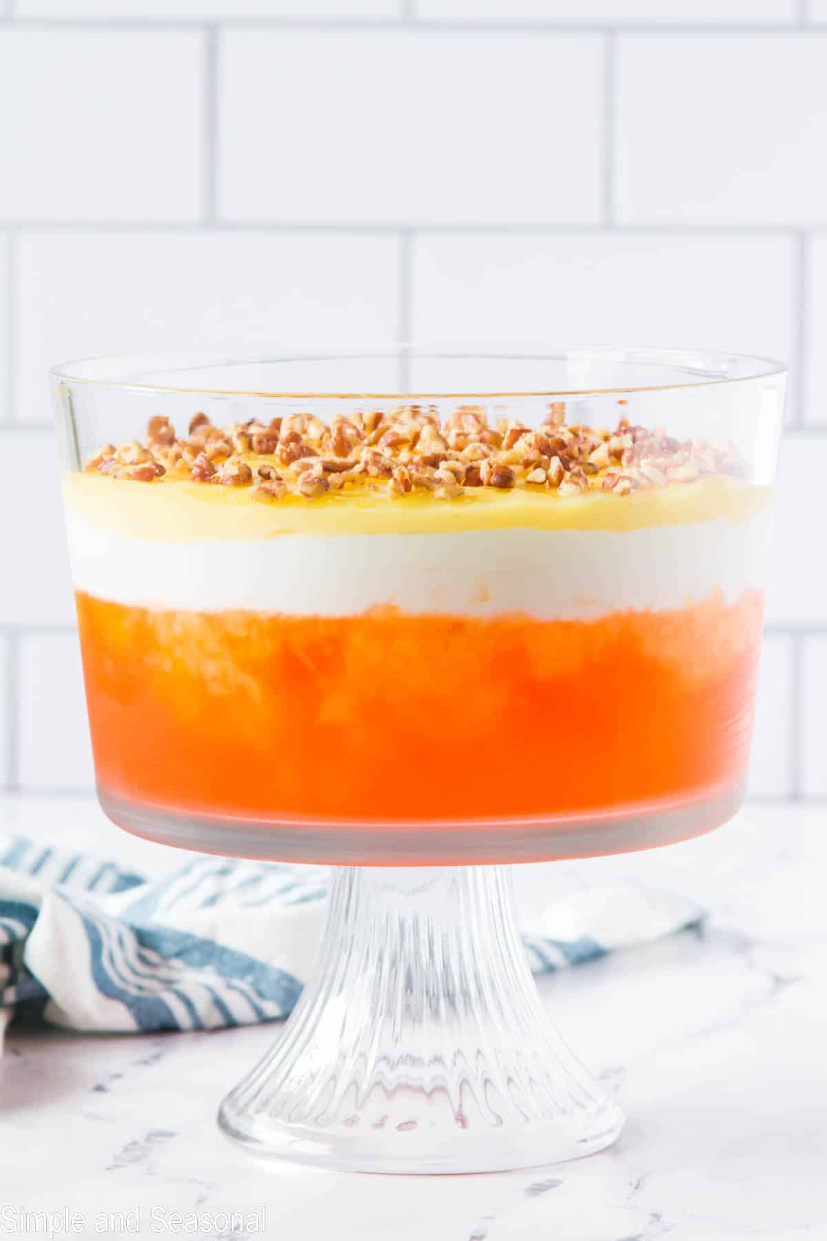 completed orange jello layered dessert with pecans on top