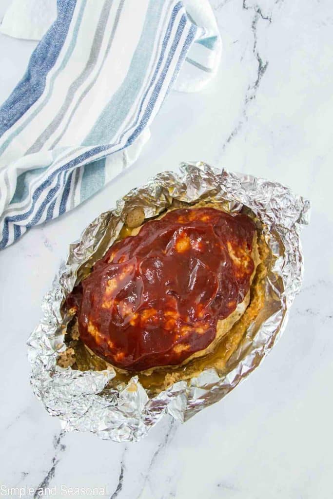 meatloaf removed from pot, still wrapped in foil, with glaze on top for broiling