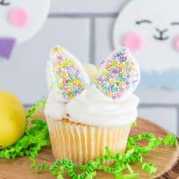 cupcake on a wooden platter with Easter bunny decorations in the background