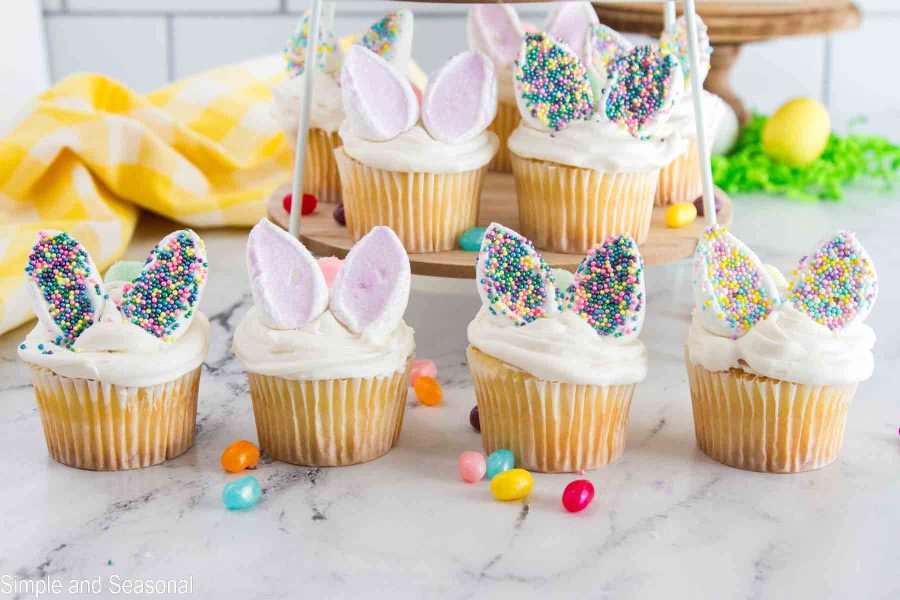 collection of pink and pastel colored bunny ears on vanilla cupcakes.