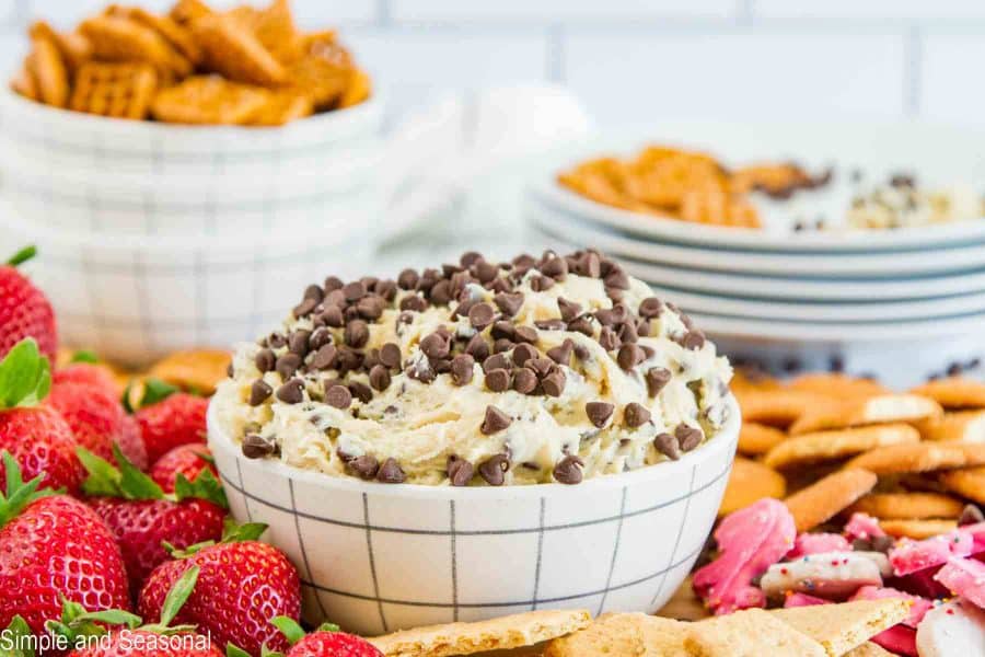 horizontal image of dip in a bowl, surrounded by items for dipping like strawberries, animal cookies and crackers