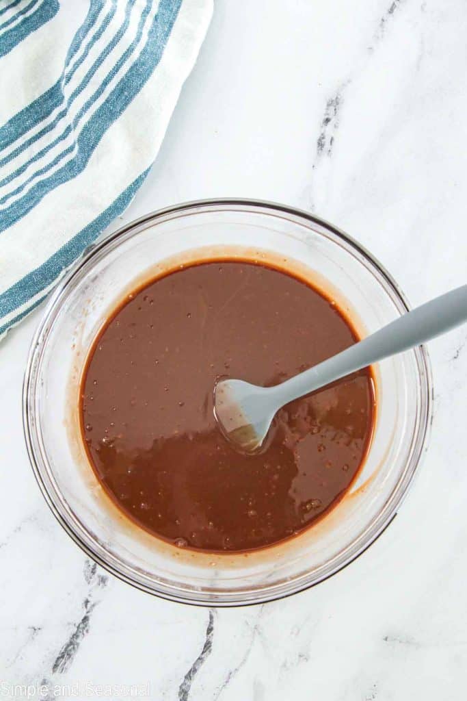 spoon stirring cream and chocolate together to create ganache