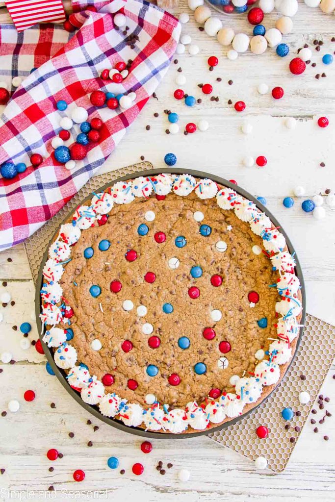Top down view of baked and frosted giant cookie cake for 4th of July with red white and blue decorations