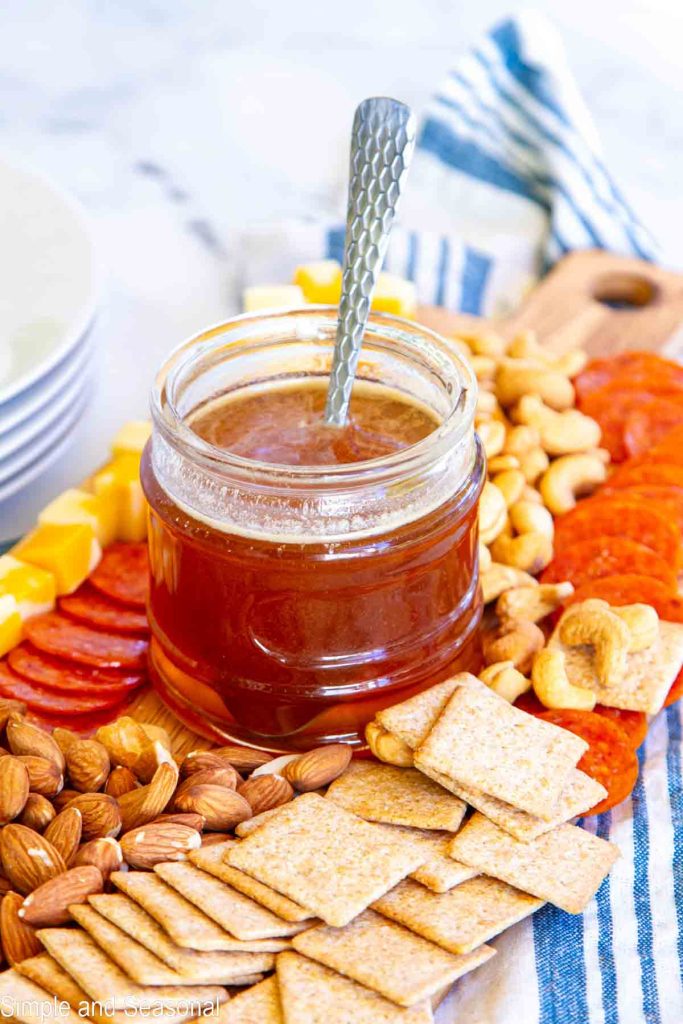 jar of honey on a platter with snacks