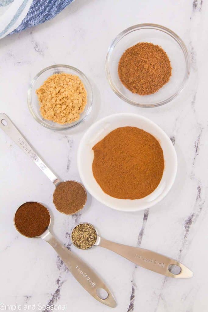 spices in bowls and measuring spoons on marble top background