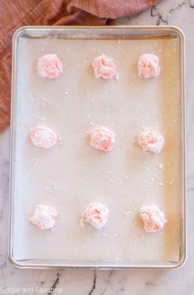 powdered cookie balls on baking sheet