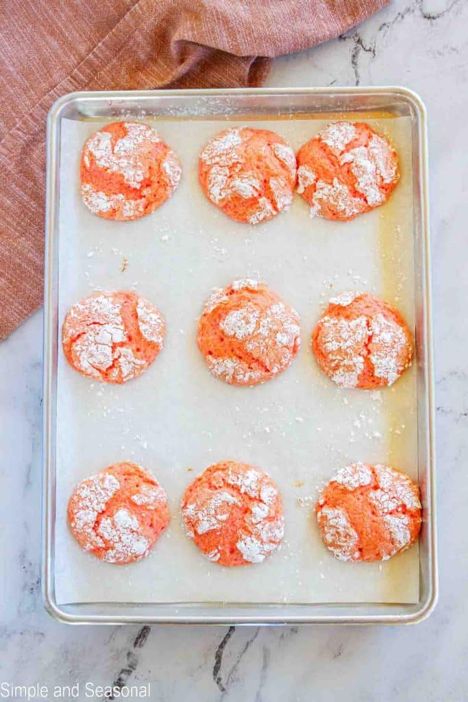 baked strawberry cake mix cookies on lined baking sheet