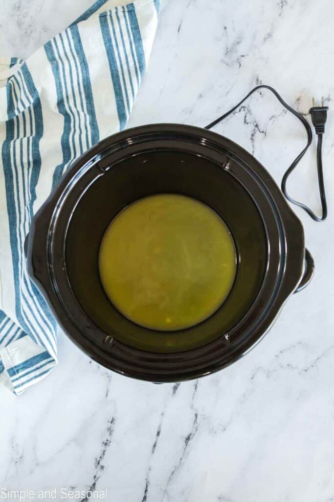 shows melted butter in the bottom of a slow cooker.