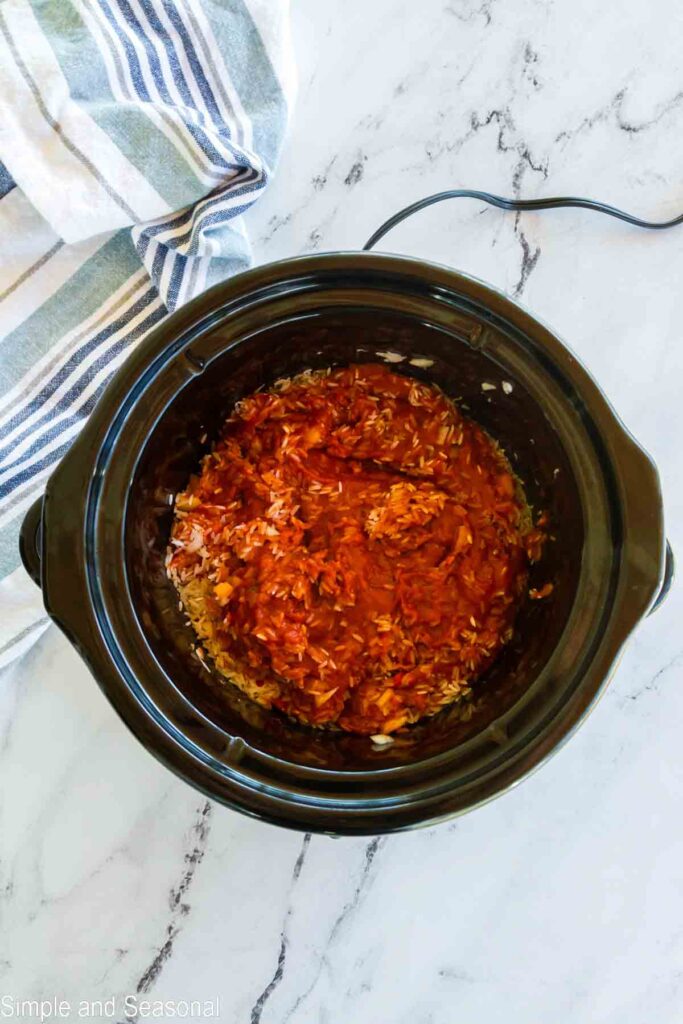 rice stirred into sauce mixture over chicken in slow cooker