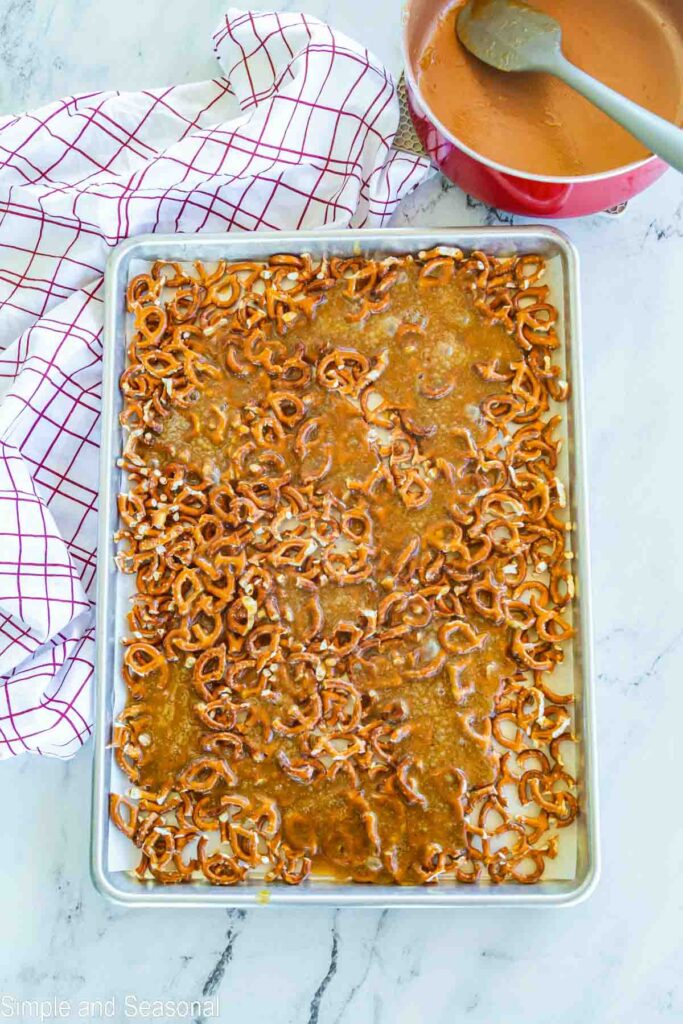 toffee mixture poured over pretzel pieces on sheet pan