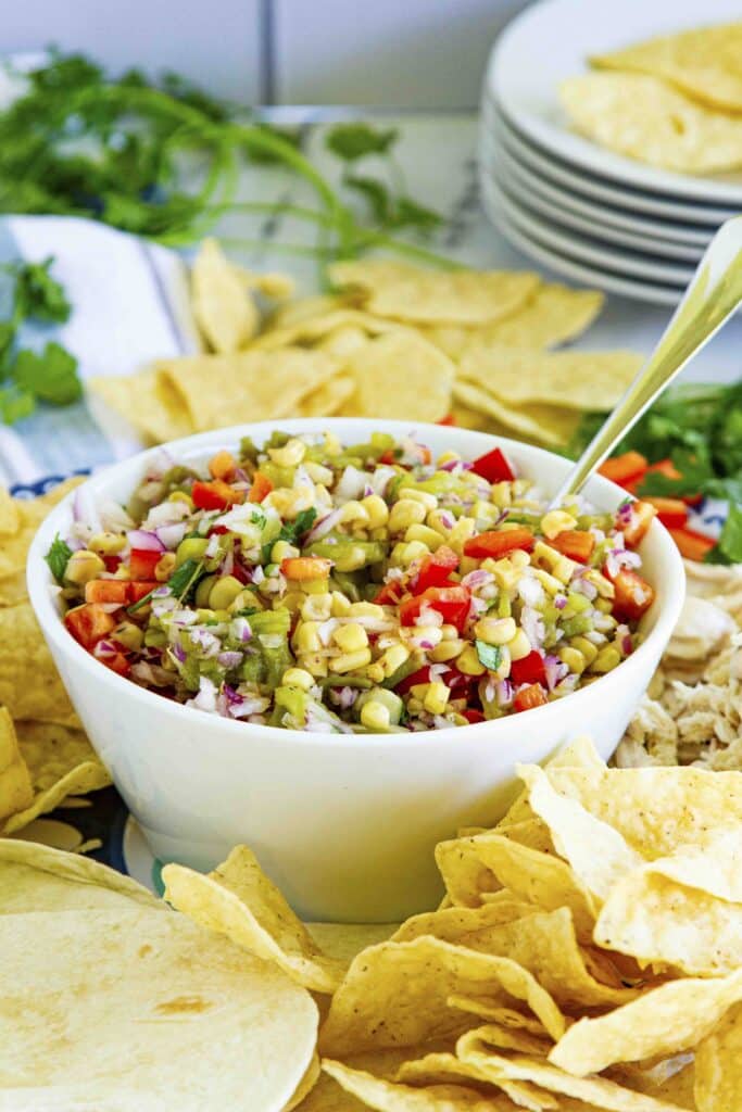 bowl of Mexican Corn Salad on platter with chips and tortillas